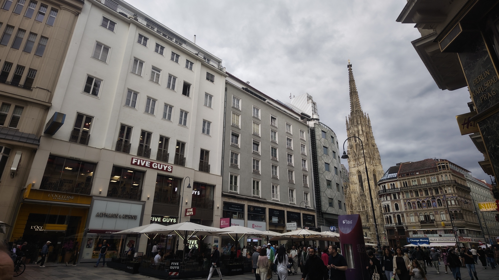 A five guys, a church, and seating and people in a Platz in Vienna