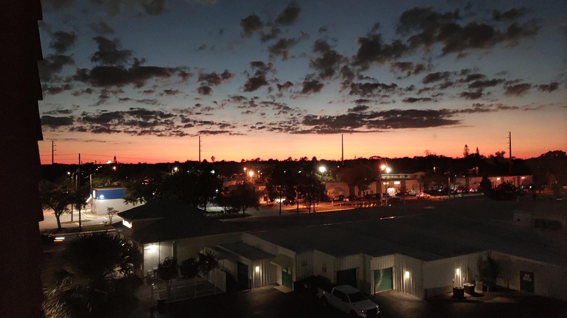 A photo of suburban California with a sunset. The sky is pink and blue with dark grey clouds