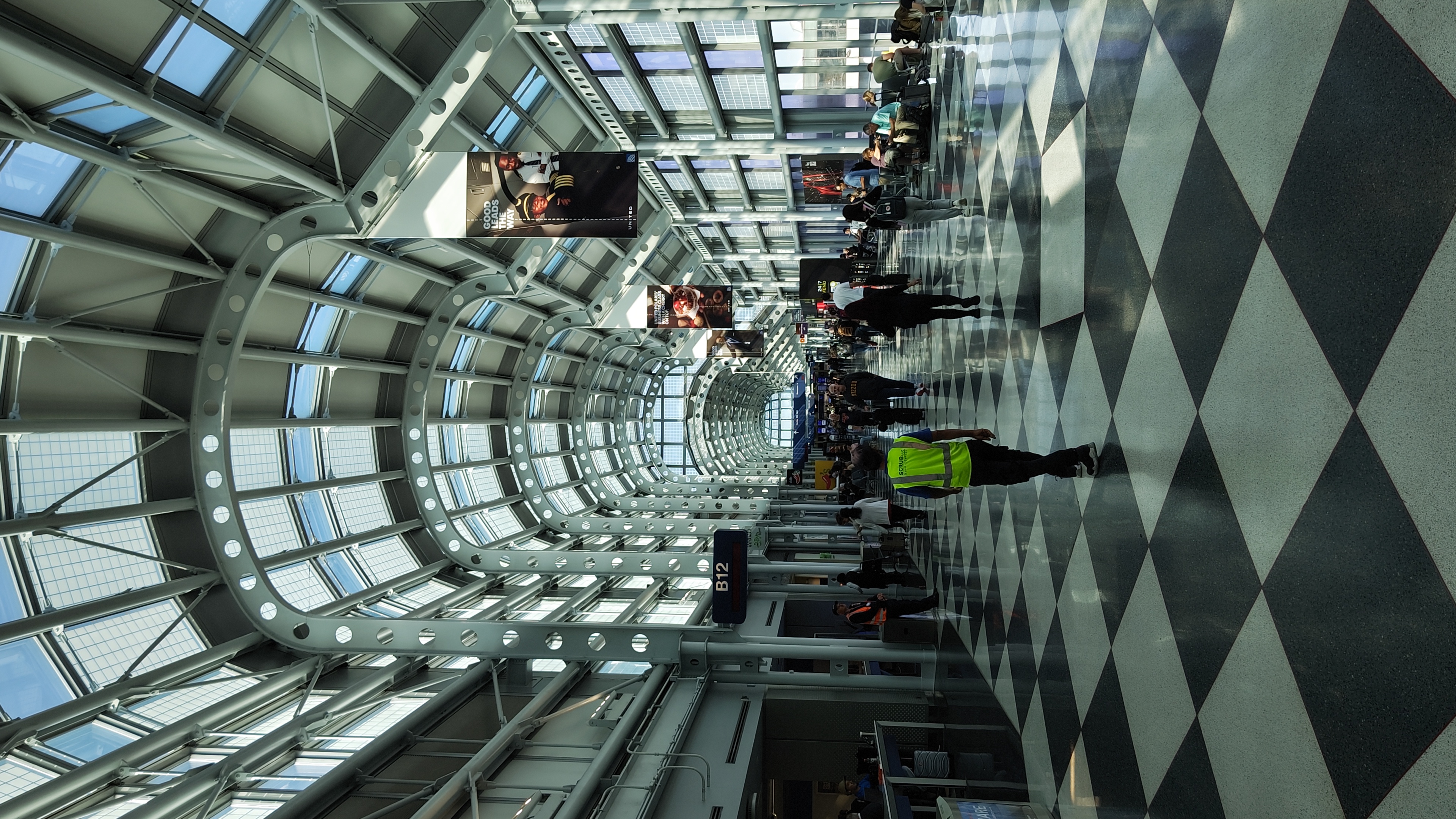 A photo in the late afternoon of O'Hare's passenger terminal interior airside. There are curved roofs with visible beams, and a tiled patterned floor.