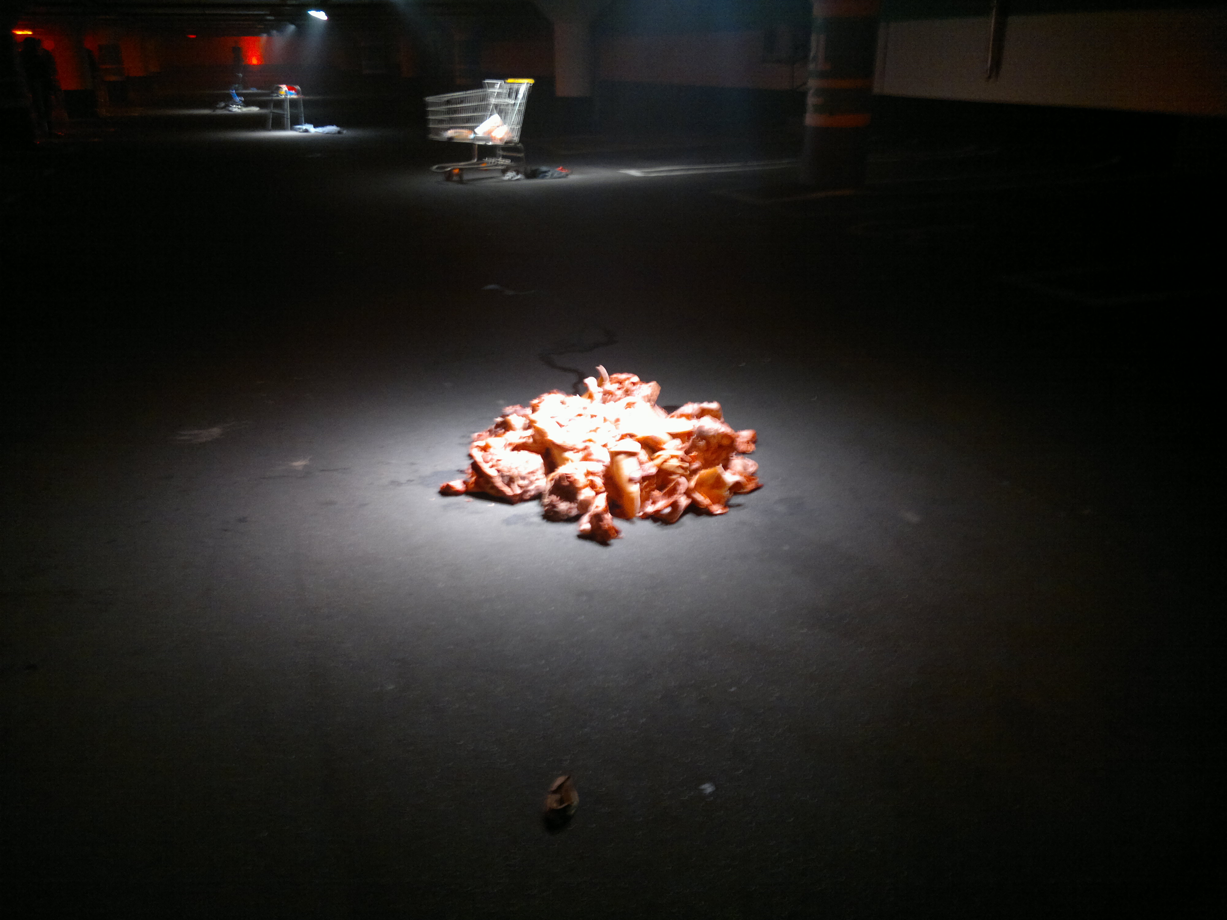 A pile of art in a dark room with a bright spotlight shining on top of it. It looks like a pile of old burger buns.